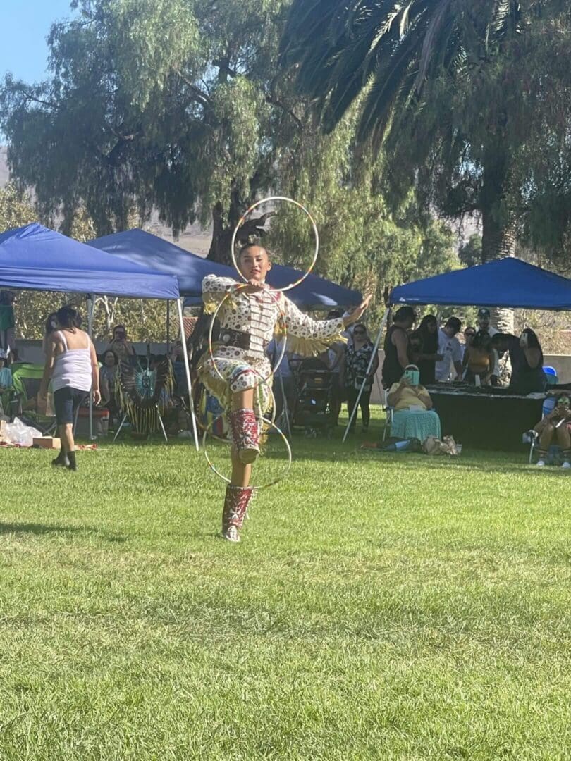 Dancer performing with hoops at outdoor event.