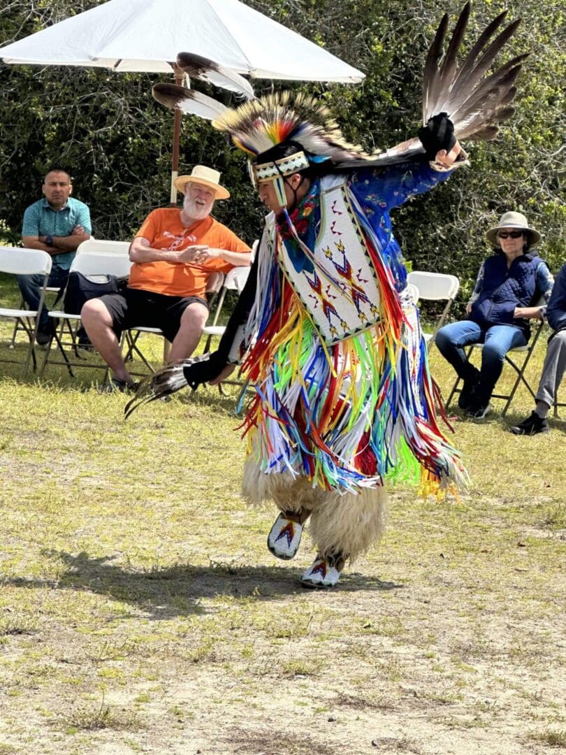Dancer in colorful traditional regalia performing outdoors.