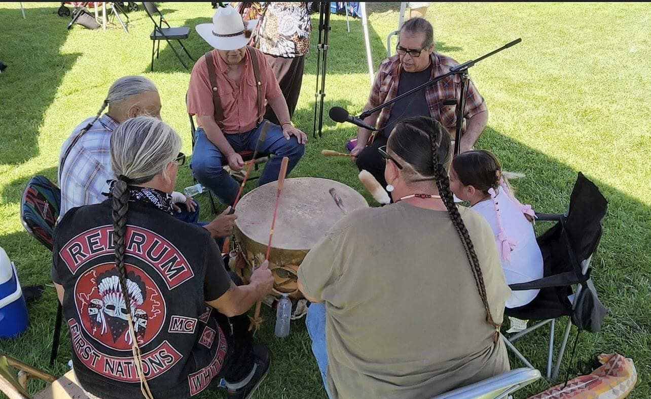 Group drumming circle outdoors on a sunny day.