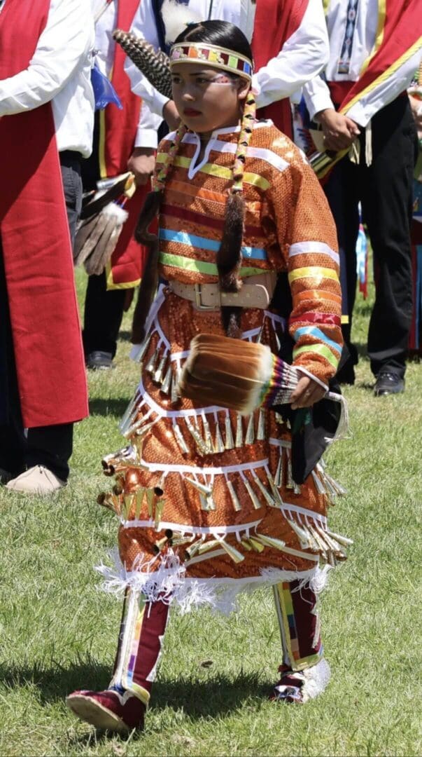 Person wearing a traditional Native American dress at an outdoor event.