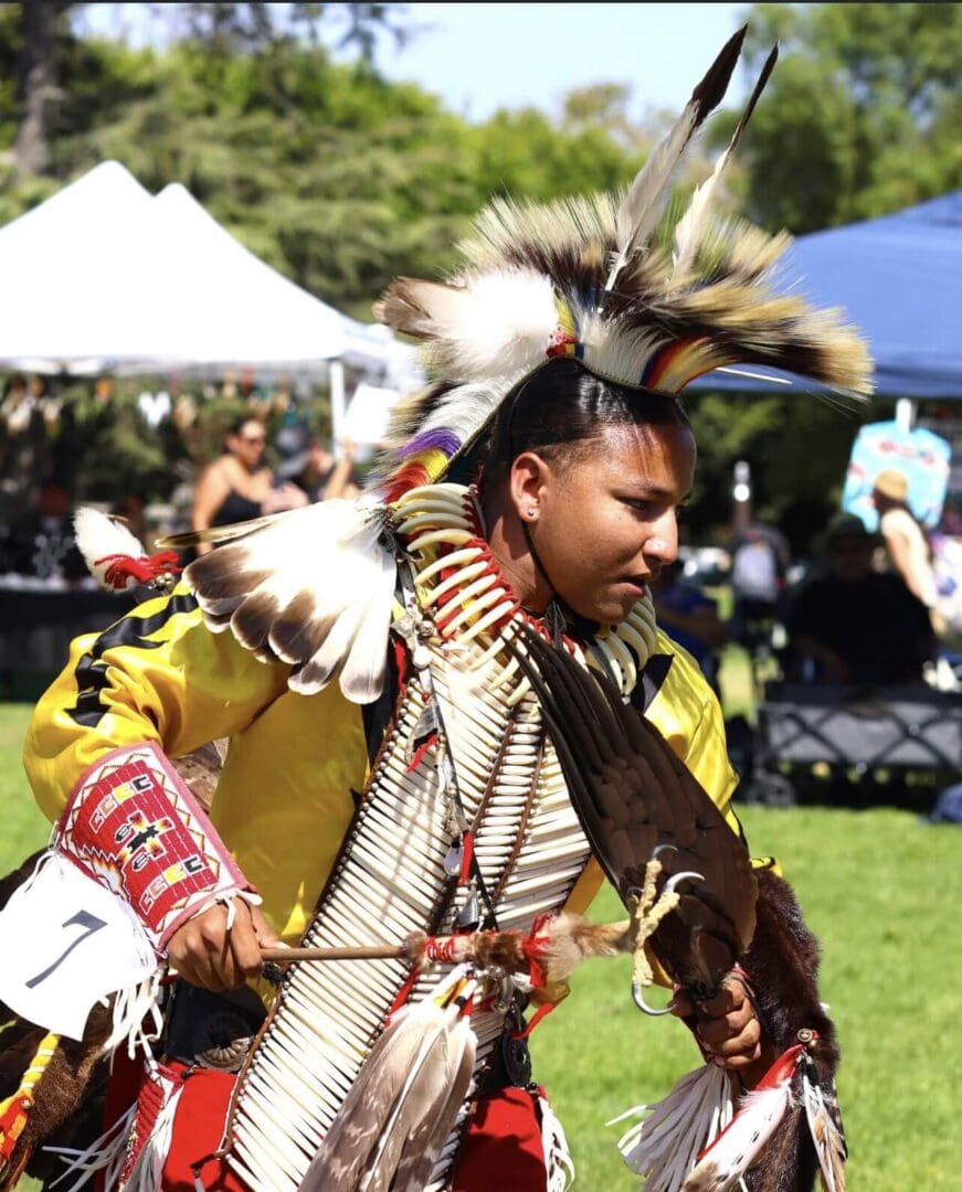 Native American man performing traditional dance in ceremonial attire.