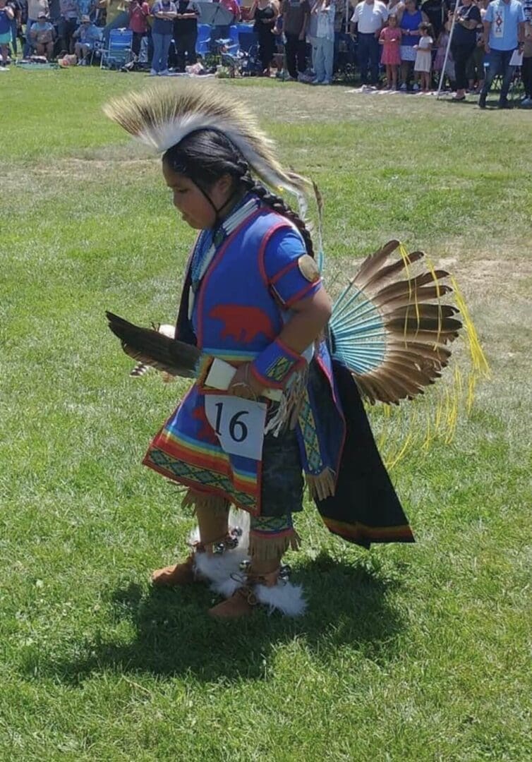 Person in traditional Native American attire at an outdoor event.