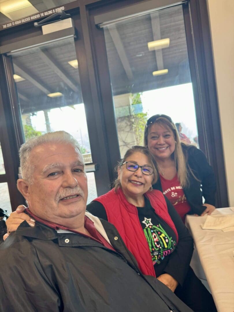 Three people smiling at a table indoors.
