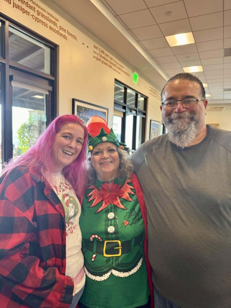 Three people smiling, one in elf costume.