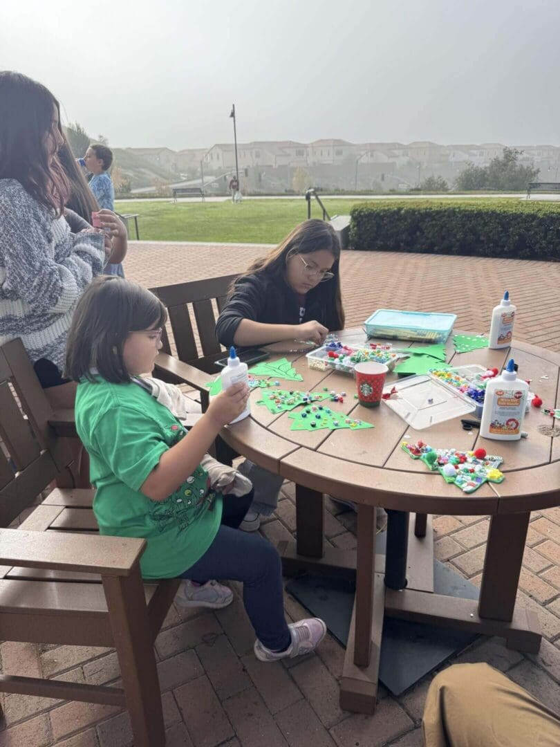 Children crafting at outdoor wooden table.