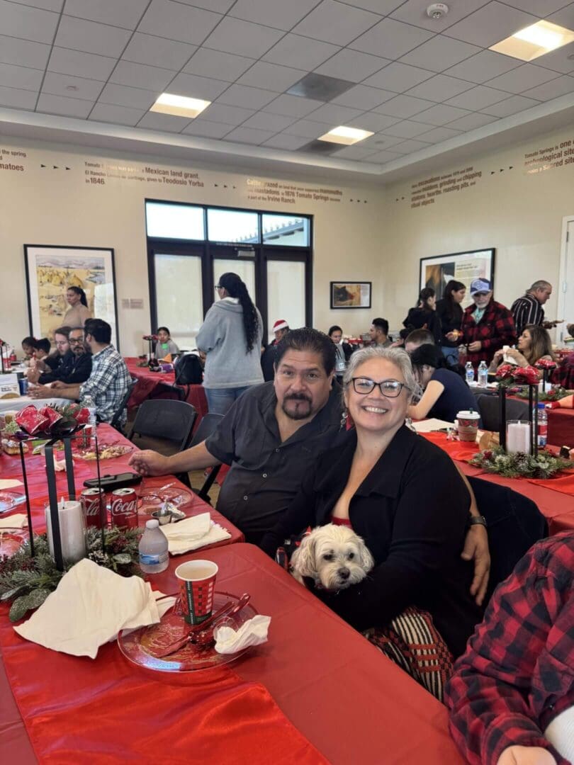 Smiling couple at festive gathering with dog.