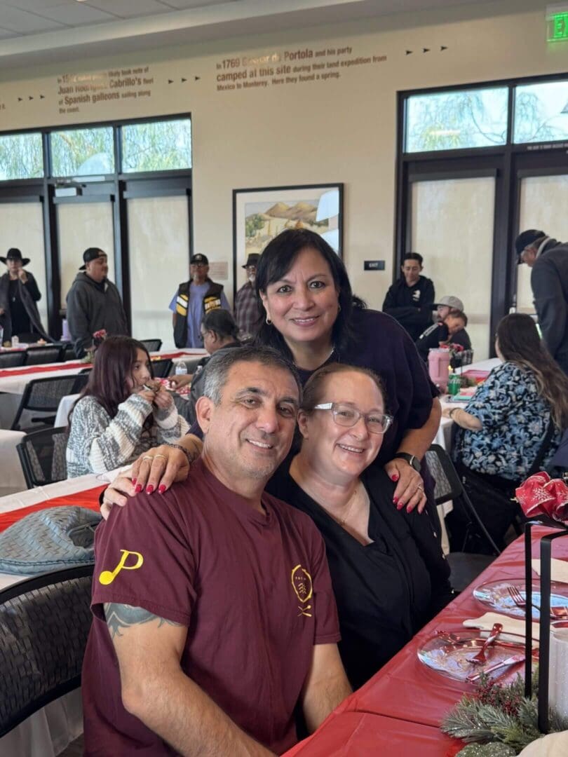Three people smiling at a festive gathering.