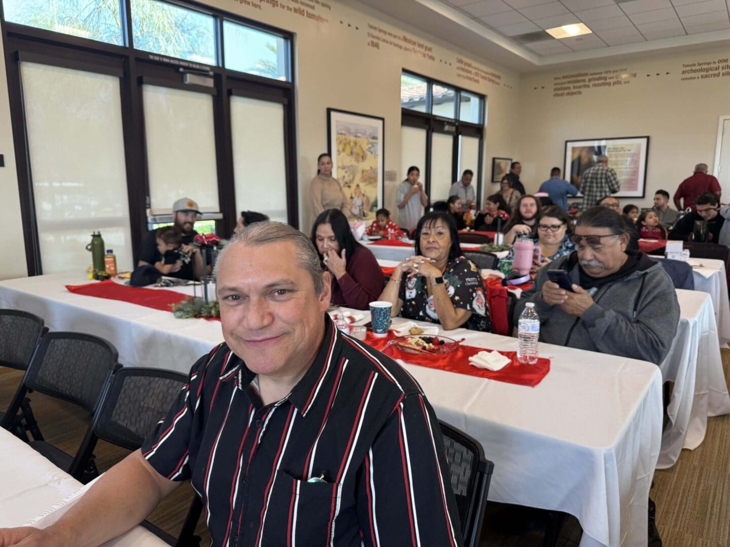 Smiling man seated at a festive gathering.