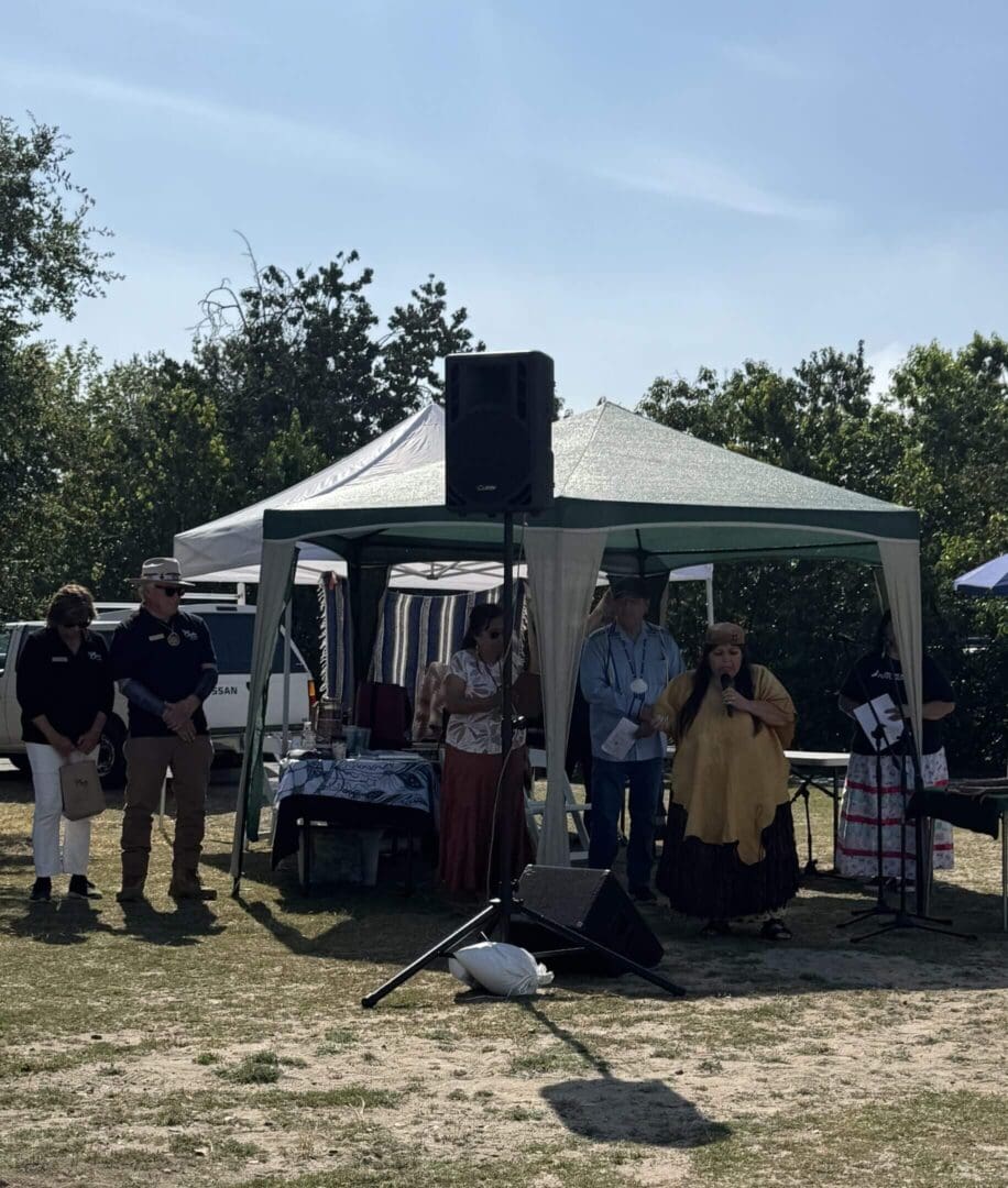 People gathered under a canopy at event.