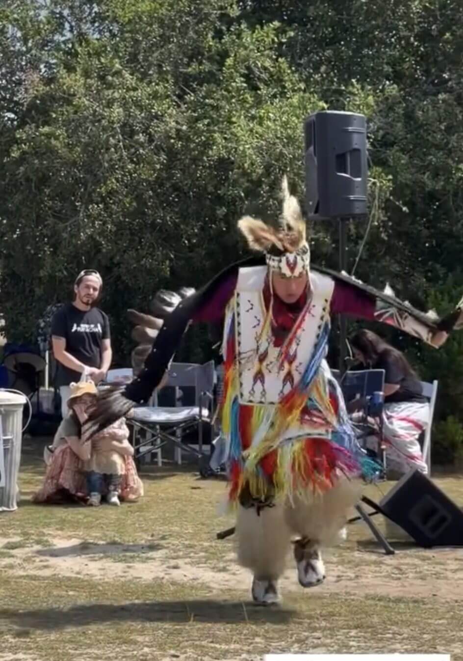 Person dancing in colorful traditional attire outdoors.